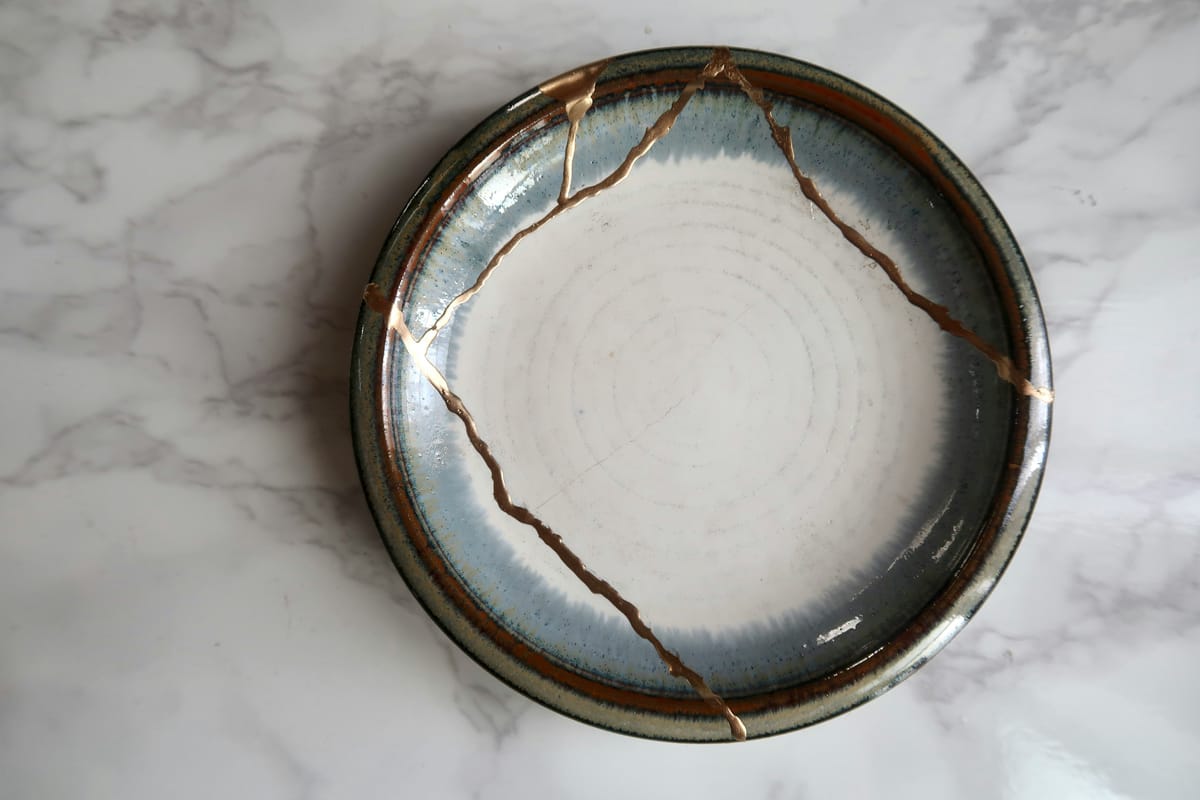 A kintsugi bowl with golden seams, symbolizing how healing trauma creates unique strength and beauty. Perfect for an article on manifestation and inner work.