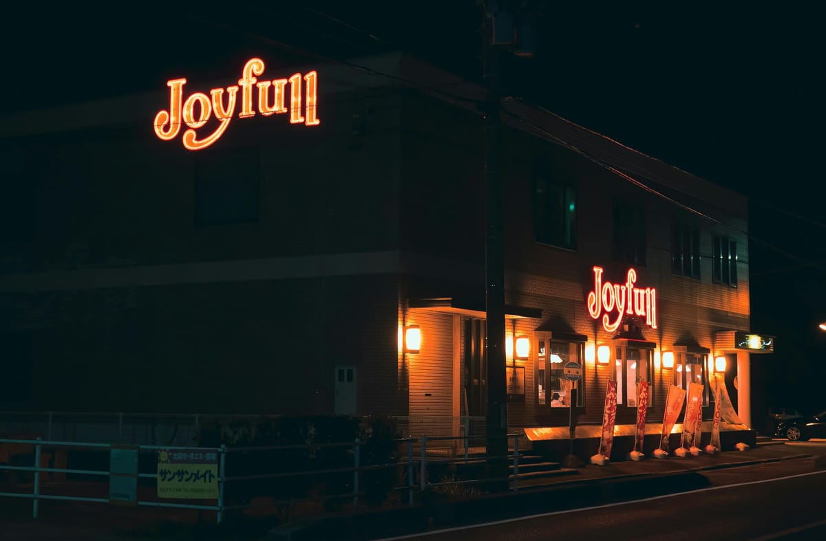 Night view of a Joyful neon sign on a brick building, representing choosing joy and positive emotions even in difficult moments