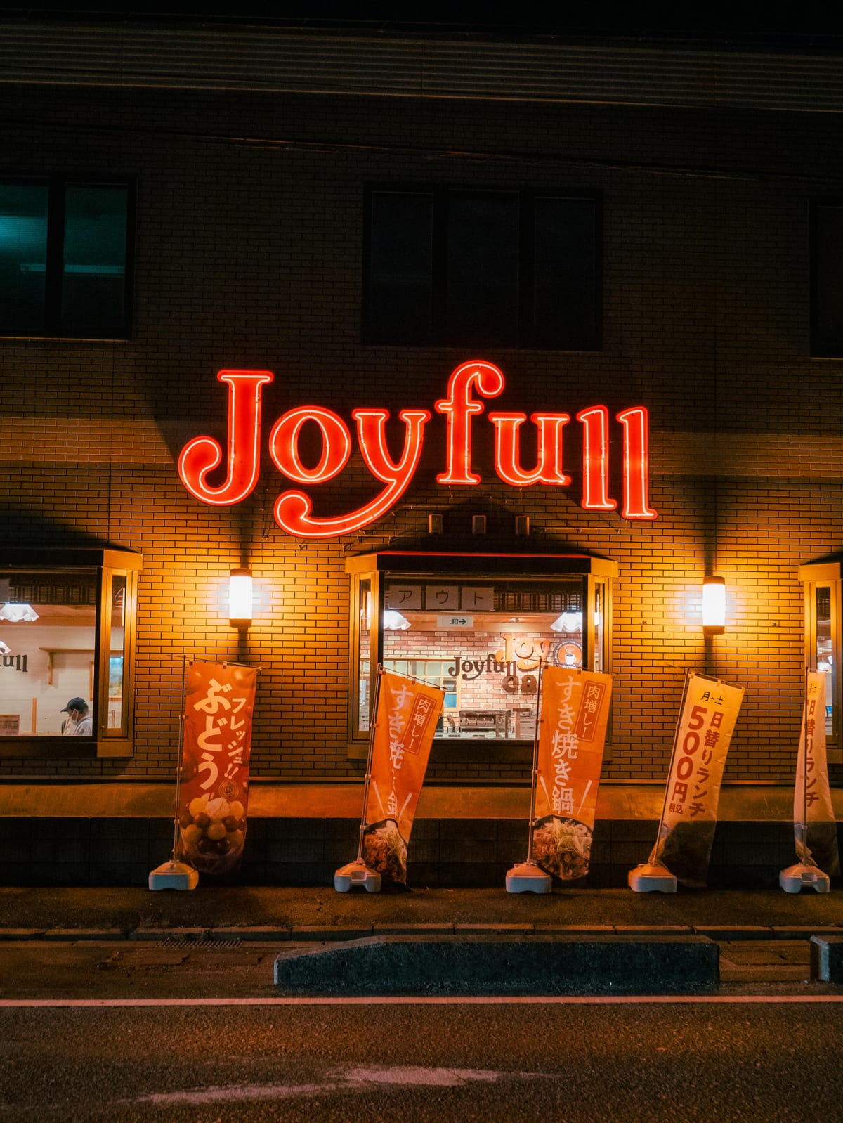 夜晚霓虹燈招牌「Joyful」在磚牆建築上，象徵即使在困難時刻也能選擇快樂與正向情緒