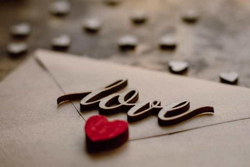 Wooden love letters and a red heart on a kraft paper envelope, representing emotional connection and love languages in relationships