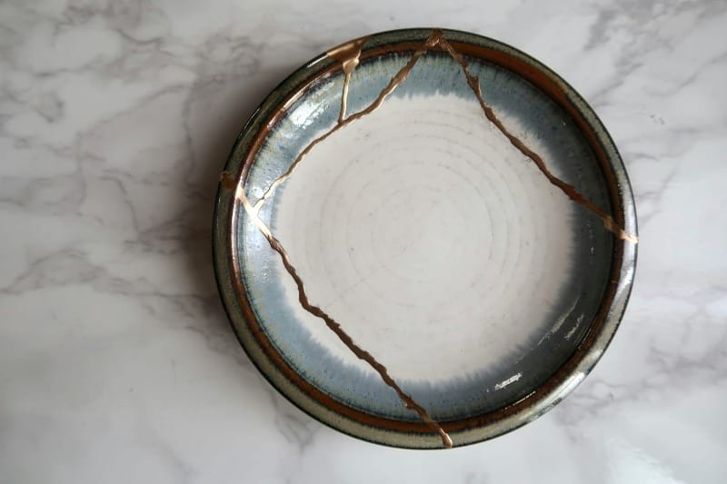 A kintsugi bowl with golden seams, symbolizing how healing trauma creates unique strength and beauty. Perfect for an article on manifestation and inner work.